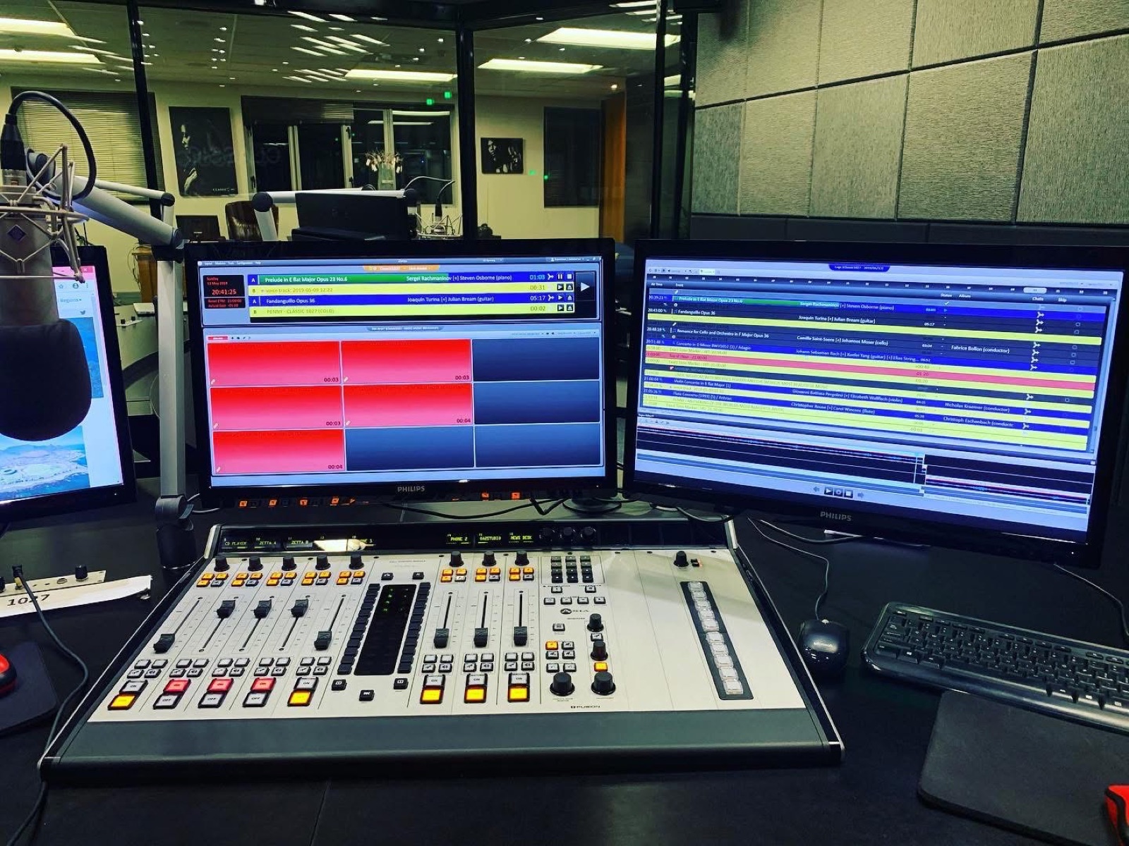 Radio studio console with playout screens, microphone arms, and presenter positions
